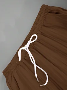 Detail view of elastic waistband and white drawstring on brown casual pants