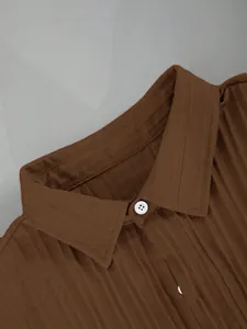 Detailed macro view of brown textured fabric and white buttons on a men's Hawaiian casual shirt