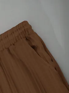 Detailed macro view showing elastic waistband and side pocket on brown casual trousers
