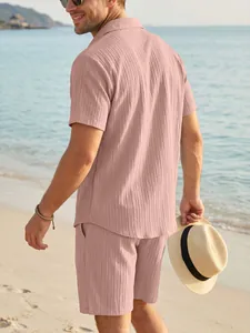 Rückansicht eines Mannes in einem rosa lässigen Hemd und Shorts Set an einem sonnigen Strand