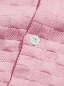 Detailed close-up showing pink jacquard fabric texture and white button on casual shirt