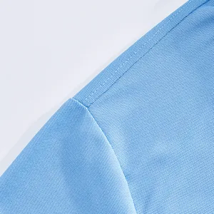 Gros plan d'un polo en soie glacée bleu clair montrant le tissu en maille respirant.