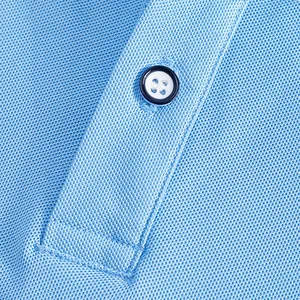 Gros plan d'un polo bleu en soie glacée montrant la texture maille et le bouton