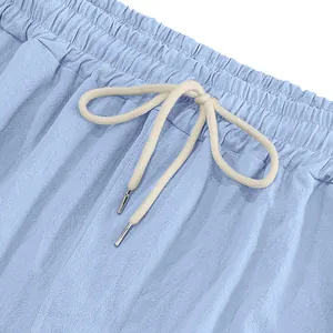 Close-up detail of light blue linen pants elastic waistband and cream drawstring