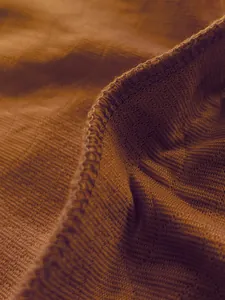 Macro view of the brown jacquard fabric texture and stitching of a men's casual t-shirt.