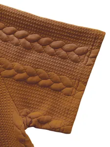 Close-up of brown men's T-shirt showing intricate jacquard weave and cable knit pattern.