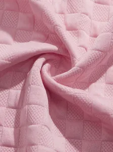 Close-up of pink jacquard fabric showing breathable textured waffle pattern detail.