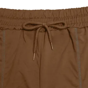 Dettaglio della vita elastica con coulisse regolabile di pantaloncini sportivi marroni.