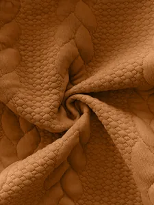 Close-up of brown textured jacquard fabric with detailed diamond and cable patterns