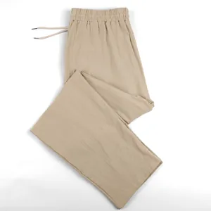 Detailed macro view of beige linen trousers for men featuring a drawstring and straight cut