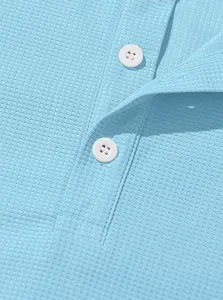 Macro view of light blue waffle knit fabric and buttons on a men's casual Henley shirt.