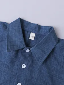 Primer plano detallado del cuello de una camisa de lino azul para niños con etiqueta talla 100