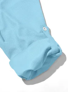 Close-up of waffle texture fabric and rollable sleeve design on light blue men's shirt