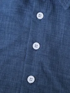 Detalle de primer plano de tela azul transpirable y botones blancos en camisa de verano