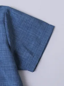 Primer plano detallado de la textura del tejido azul transpirable en camisa de niño de verano