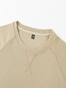 Detalle de la textura de punto gofrado caqui y cuello redondo de camiseta