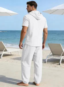 Rückansicht von Herren-Set aus weißem Leinenhemd mit Kapuze und Hose am Strand