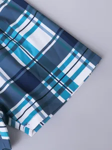 Primer plano de la tela transpirable a cuadros azules de una camisa de verano para niño.