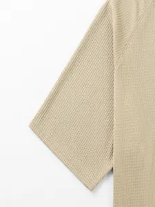 Detalle del tejido de punto gofrado beige y costuras de manga raglán en una camiseta