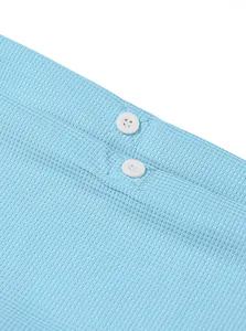 Close-up detail of light blue waffle knit fabric texture and white buttons on a men's shirt