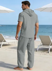 Rückansicht eines grauen Herren-Kapuzenshirts und einer langen Hose am Strand