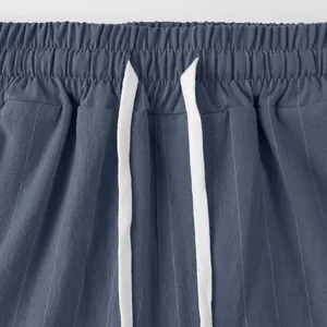 Close-up of elastic waistband and white drawstring on striped linen casual pants.