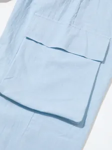 Macro view of light blue breathable linen cargo pants showing detailed side pocket flap