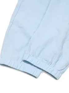 Close-up detail of light blue linen pants showing elasticated cuffs and fabric texture.