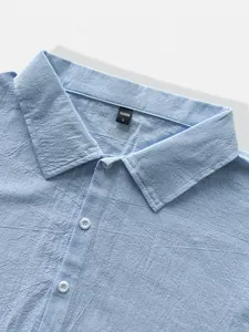 Detailed macro view showing the collar and textured fabric of a light blue linen shirt