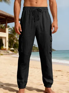 Detailed view of men's black linen cargo pants with drawstring on a tropical beach
