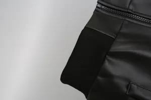 Detail of boys black PU leather jacket showing ribbed cuff and zipper texture