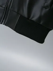 Close-up of black PU leather jacket hem showing ribbed elastic and zipper detail.