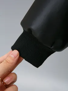 Detail view of a black PU leather jacket cuff featuring elastic ribbed knit design