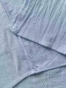 Close-up detail of blue linen fabric texture and stitching of a long-sleeved shirt