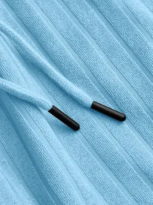 Detail view of light blue ribbed knit fabric with drawstring and black plastic tips