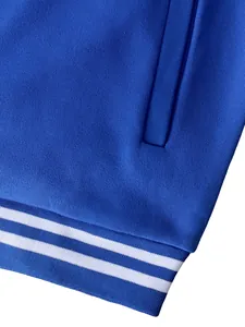 Close-up detail of a blue American style baseball jacket showing striped ribbed hem and pocket.