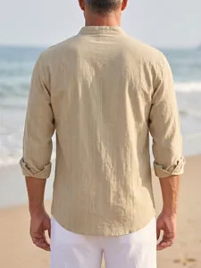 Back view of a men's beige pinstripe linen shirt with stand collar on a beach background.