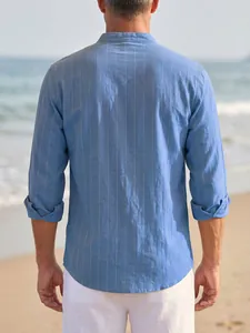 Rear view of a men's blue vertical striped linen shirt with stand collar at the beach