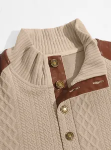 Close-up detail of beige jacquard knit sweater with standing collar and leather trim