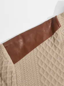 Close-up of textured jacquard knit sweatshirt with brown faux leather shoulder patch