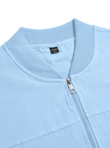 Close-up detail of a light blue bomber jacket featuring a ribbed collar and metal zipper.
