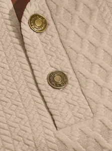 Close-up of textured jacquard knit sweatshirt with metal buttons and shoulder patches
