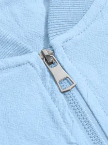 Detailed macro view of a silver metal zipper on a light blue fabric bomber jacket