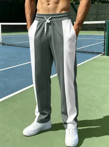 Stilvolle grau-weiße Color-Block-Jogginghose für Herren, getragen auf einem Tennisplatz