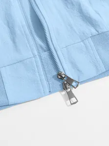 Detailed view of the two-way silver zipper on a light blue sports jacket with ribbed hem