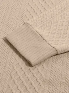 Close-up of textured jacquard fabric and ribbed cuff on a tan men's sweatshirt