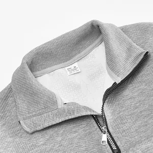 Detailopname van grijze sweatshirt met kwartritssluiting en jacquard gebreide textuur