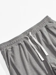 Detail shot of grey corduroy pants showing the waistband and white drawstring texture.