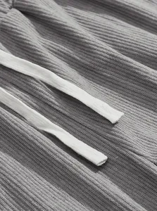 Close-up of gray corduroy fabric texture and white drawstrings on men's cargo pants.