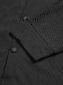 Macro detail showing the ribbed texture and cuff of a heavyweight black corduroy shirt